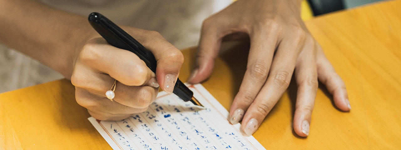 万年筆で葉書を書いている