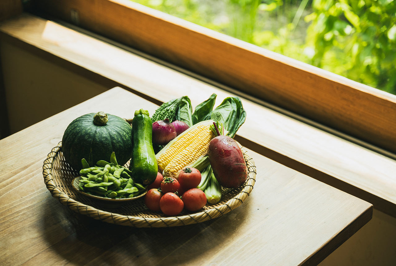 ざるに枝豆やかぼちゃ、とうもろこしなどのたくさんの夏野菜がのっている