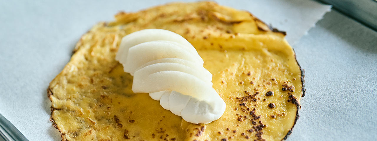 へこ焼きの生地に生クリームと梨がのっている