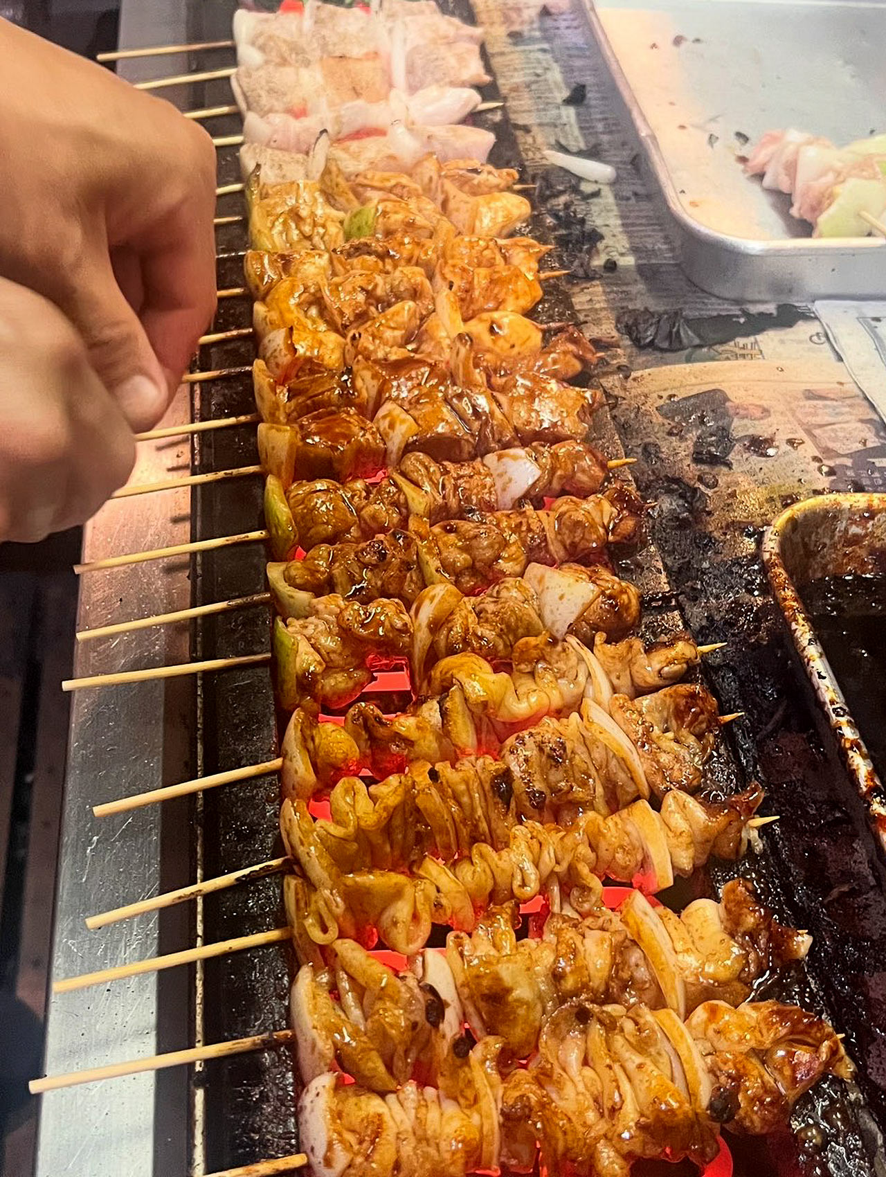 〈焼とり丸ちゃん〉の厨房で、炭火でたくさんの焼き鳥が焼かれている