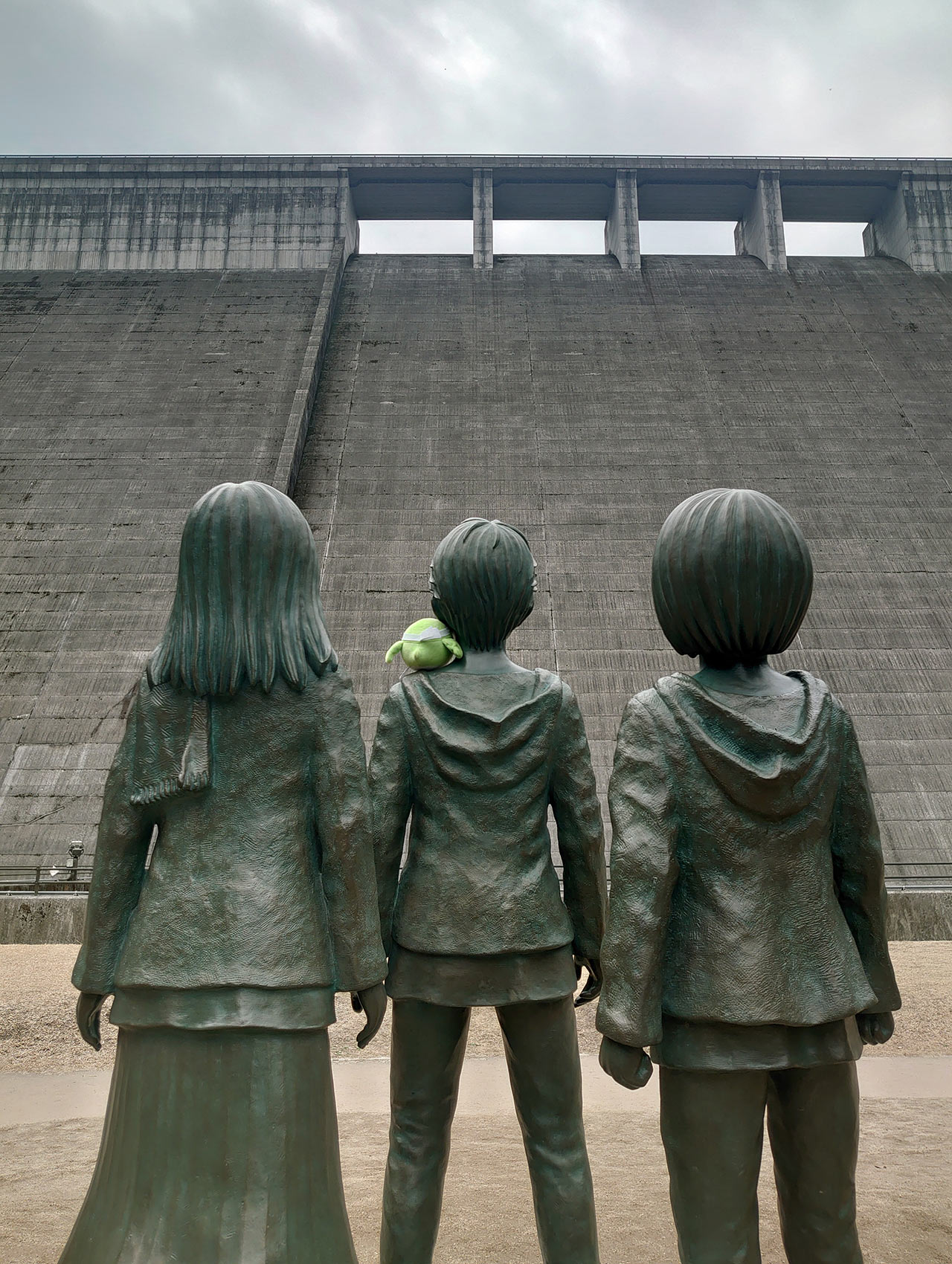 『進撃の巨人』のエレンたちの銅像とめじろんが大山ダムを見上げる