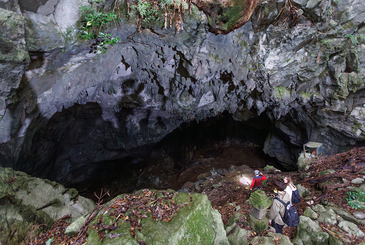 洞窟の入口を進んでいくアクティビティガイドと参加者