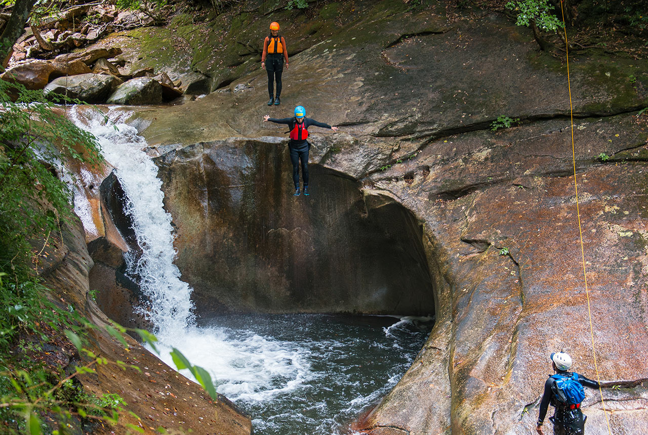 「藤河内渓谷」で滝壺に飛び込むアクティビティ体験者