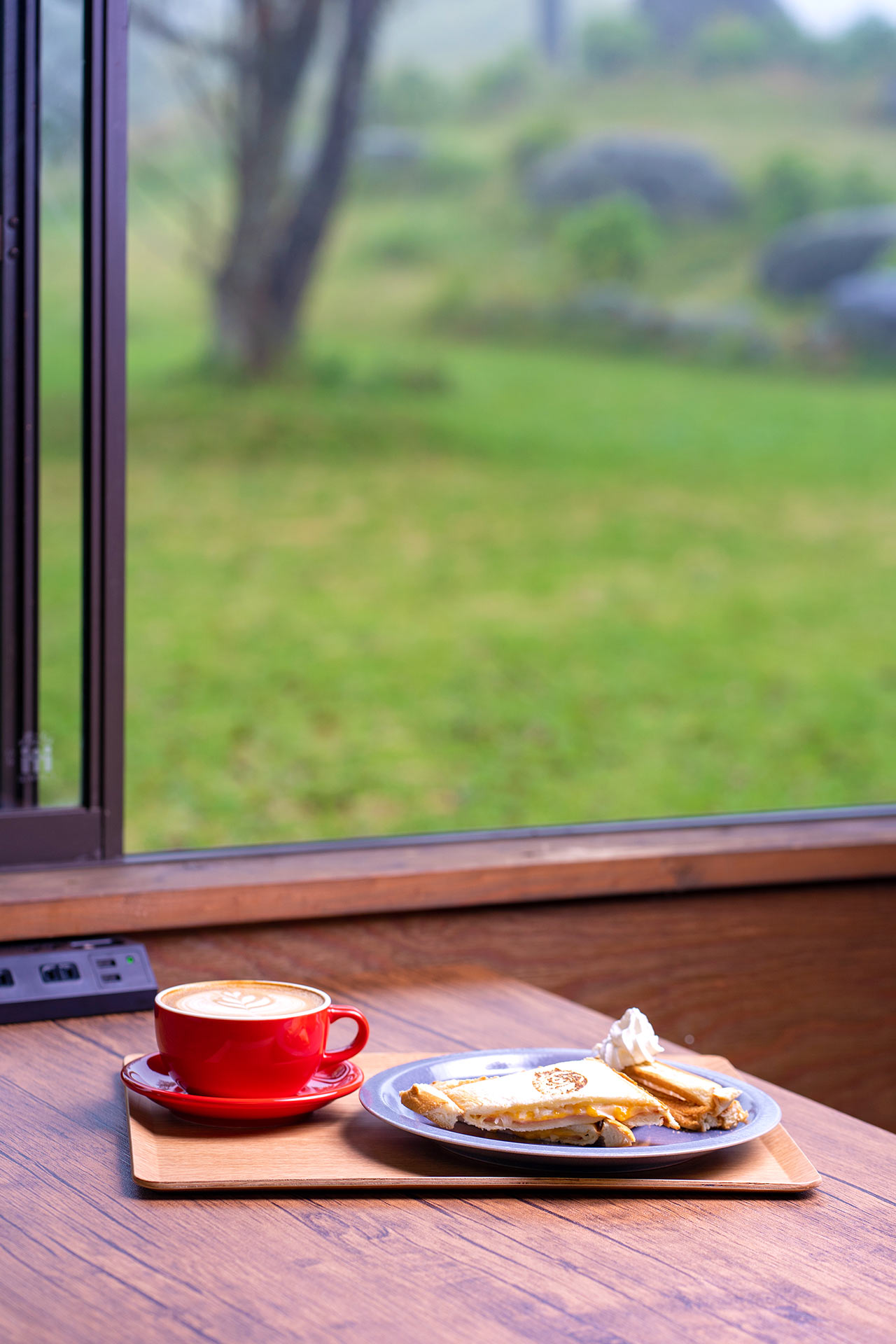 〈Cafe Procione〉の窓際のテーブルにホットサンドとカフェラテが置かれている