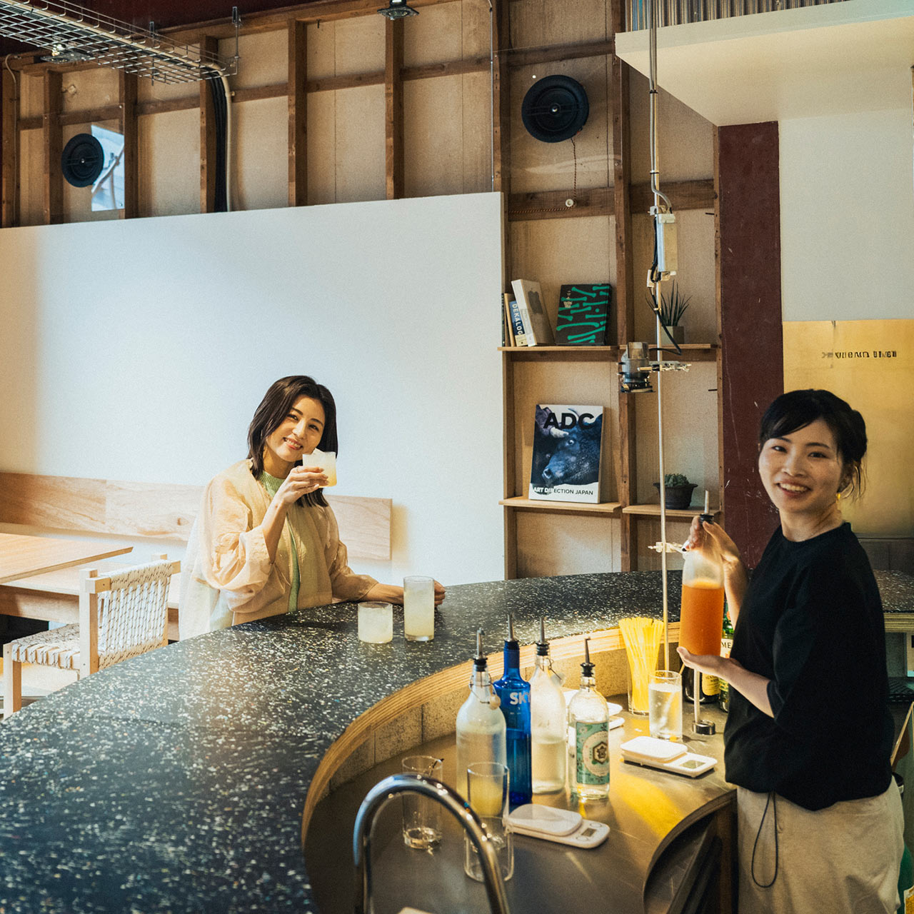 レモンサワーを手にする宇賀なつみさんとカウンター内のスタッフさん
